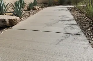 Concrete walkway with control joints and agave plants in the midday sun in Phoenix, AZ.