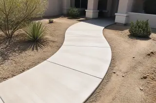 Cured concrete walkway with natural edges and desert landscaping in the bright midday sun in Phoenix, AZ.
