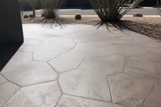 Stamped concrete surface with a stone texture beside desert cacti and gravel in Phoenix, AZ.