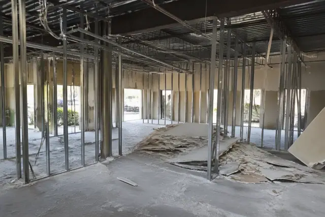 Commercial demolition progress of an office interior with exposed metal studs and debris in Phoenix, AZ.