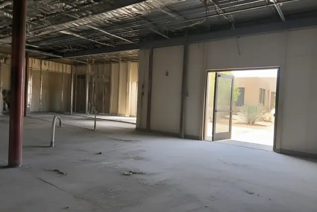 Interior of a commercial building undergoing demolition with exposed studs and utilities in Glendale, AZ.