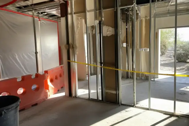 Partially dismantled drywall and metal stud wall with safety barriers at a commercial jobsite in Phoenix, AZ.