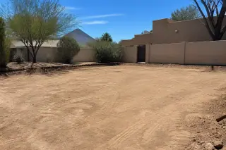 Level dirt grade on a residential lot with stucco homes in Phoenix, AZ.