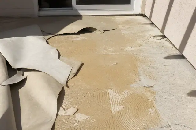 Vinyl flooring being removed from a subfloor during a renovation project in Phoenix, AZ.