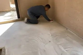 Technician cleaning a prepared subfloor surface with exposed adhesive residue in a Phoenix, AZ home.