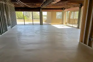 Clean concrete floor in a gutted commercial office space with exposed studs and overhead conduits in Phoenix, AZ.