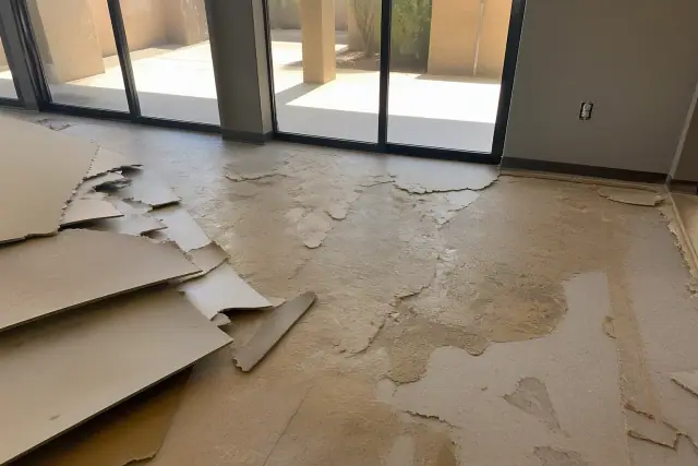 Torn vinyl flooring and adhesive residue on a subfloor during commercial demolition in Phoenix, AZ.