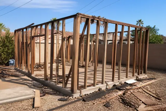 Partial demolition of a wooden garage structure with debris on the ground in a backyard in Glendale, AZ.