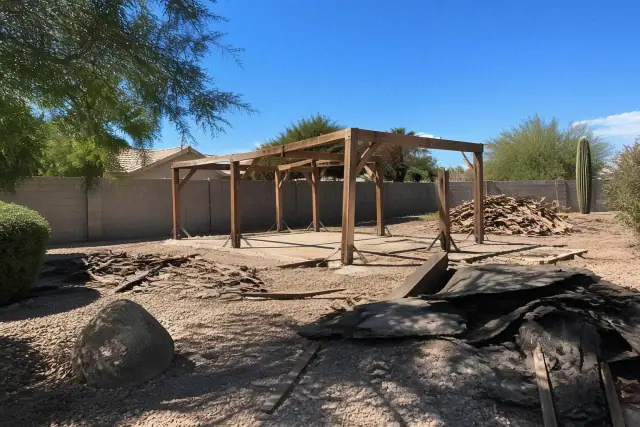 Piles of wood scrap and torn roofing materials during a garage and shed demolition in Surprise, AZ.