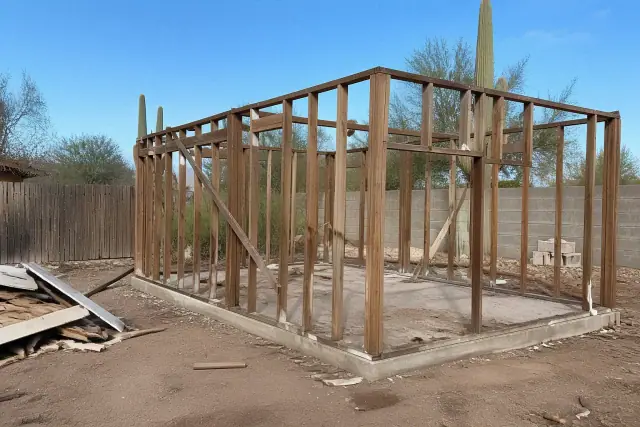 Skeletal wooden framework of a garage during a demolition project in Mesa, AZ, with desert landscaping in the background.
