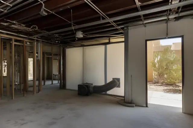Hazardous materials abatement site showing exposed studs, conduits, and desert landscape through an open door in Phoenix, AZ.