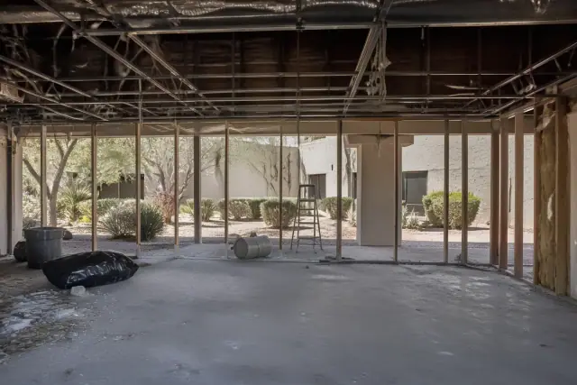 Interior demolition site with exposed studs and utilities in Tempe, AZ, seen through a doorway with desert landscaping.