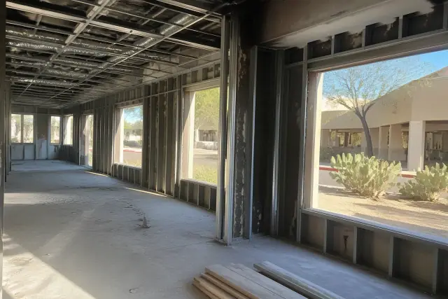 Interior demolition of a commercial office in Scottsdale, AZ, showing exposed studs and desert views through windows.