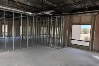 Raw structural studs and exposed metal ceiling conduits in a gutted interior space in Phoenix, AZ.