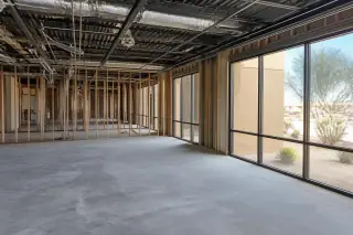 Empty commercial office interior with exposed metal studs and ceiling conduits after demolition in Phoenix, AZ.