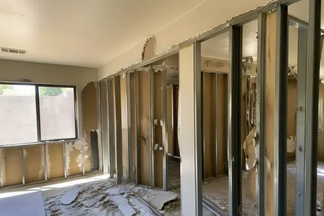 Interior wall removal with metal studs and drywall debris during a renovation in Phoenix, AZ.