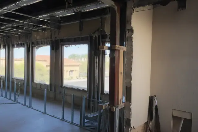 Interior of a demolition site in Phoenix, AZ, showing exposed structural studs and utility conduits.
