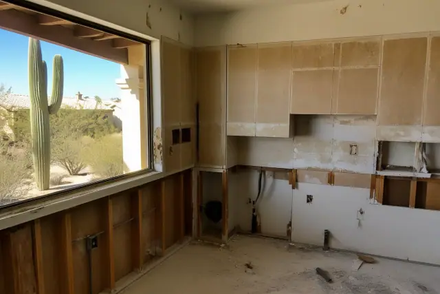 Interior of a house undergoing demolition with exposed wall framing and view of desert landscaping in Peoria, AZ.