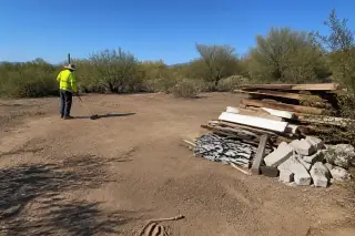 Contractor inspecting a cleared residential lot in Phoenix, AZ with desert shrubs under midday sun.