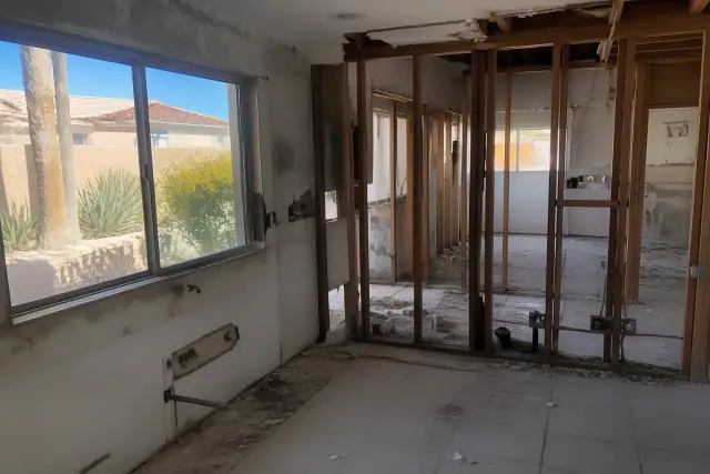 Residential interior demolition with exposed wood studs and debris at a renovation site in Phoenix, AZ.