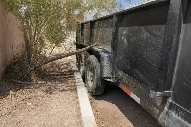 Heavy haul trailer stuck near desert landscaping and sorted construction waste in a Phoenix, AZ residential passage.