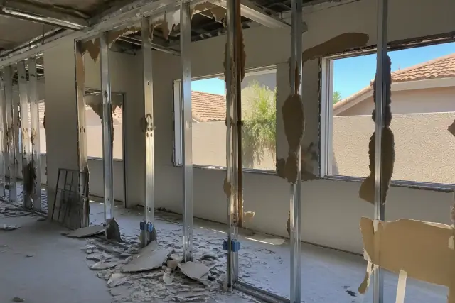 Selective demolition of a partition wall with exposed metal studs and drywall debris at a job site in Goodyear, AZ.