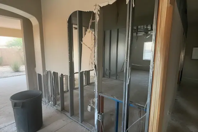 Interior selective demolition of a residential partition wall with exposed metal studs in a Surprise, AZ home.