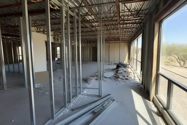 Selective demolition in progress at a commercial office space in Scottsdale, AZ, with exposed studs and overhead conduits.