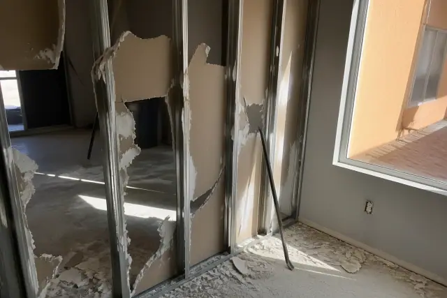 Selective demolition of a drywall partition wall with exposed metal studs at a jobsite in Mesa, AZ.