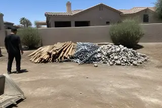 Contractor standing near a pile of sorted wood, metal, and masonry waste on a demolition site in Phoenix, AZ.