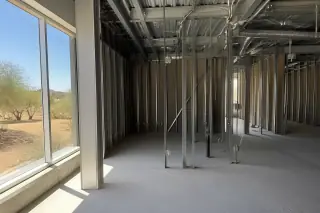 Raw structural studs and overhead metal conduits in a gutted commercial space in Phoenix, AZ.