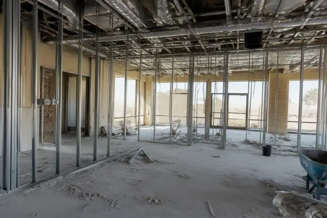 Interior demolition in progress with exposed studs and overhead conduits at a construction site in Phoenix, AZ.