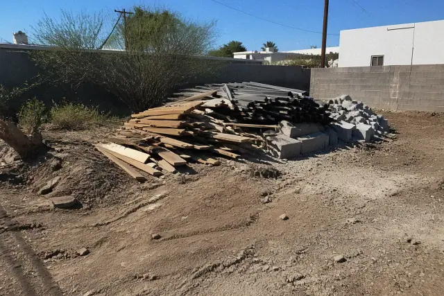 Cleared debris pile of wood, metal, and masonry at a demolition job site in Tempe, AZ under bright desert sun.