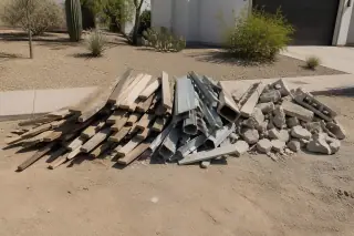 Sorted pile of wood, metal, and masonry waste in a xeriscaped Phoenix, AZ yard under bright sun.