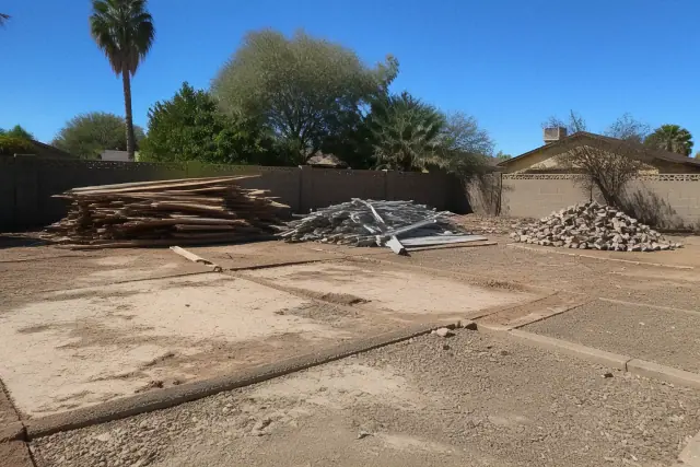 Leveled construction site with piles of sorted scrap wood and metal in a Phoenix, AZ yard.