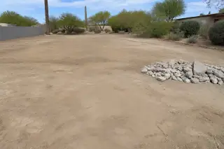 Leveled desert soil with a small pile of sorted concrete rubble on a cleared residential site in Phoenix, AZ.