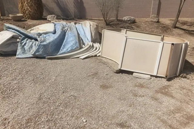 Construction workers removing a vinyl pool liner at a demolition site in Phoenix, AZ.
