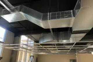 Galvanized steel air ducts above a commercial ceiling grid in a Phoenix, AZ building.