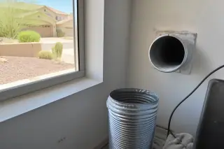 Disconnected dryer exhaust pipe showing cleaned lint at a laundry room vent in Phoenix, AZ.