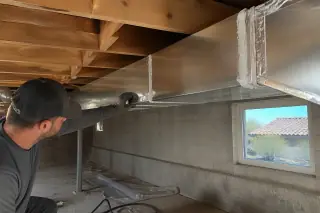 Mastic-sealed metal ductwork seams near a basement window with desert views in Phoenix, AZ.