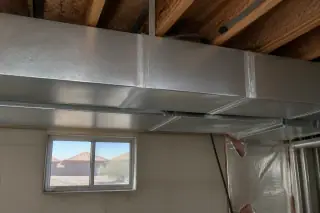 Metallic mastic sealant on silver metal ductwork seams in an unfinished Phoenix, AZ basement.