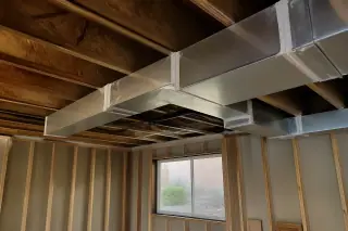 Sealed silver metal air ducts with mastic at joints in an unfinished Phoenix, AZ basement with a view of xeriscaping.