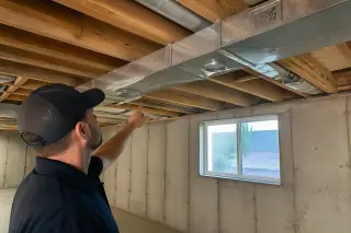 Cleaned metal air ducts and floor joists in an unfinished Phoenix, AZ basement with a view of a xeriscaped yard.