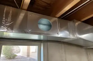 Cleaned silver air duct with a new access port and foil-taped joints in a Phoenix, AZ basement.
