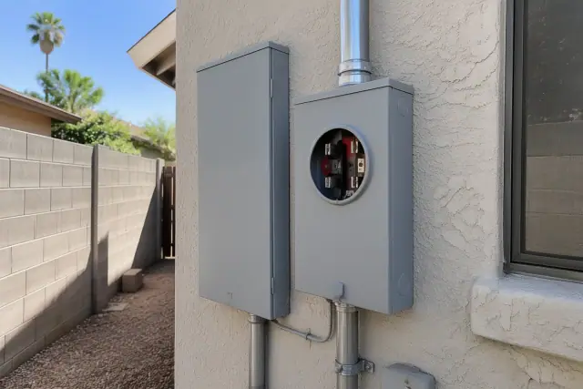 Electrical meter box replacement and 200 amp service upgrade on a stucco wall in Phoenix, AZ.