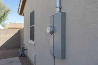 Utility meter socket and main breaker enclosure on a stucco wall in Phoenix, AZ.