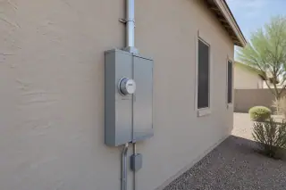 Wide view of a 400 Amp service upgrade on a stucco wall with desert landscaping in Phoenix, AZ.