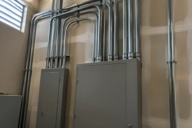 Heavy-gauge metal conduits on a tan stucco wall during a commercial electrical upgrade in Surprise, AZ.