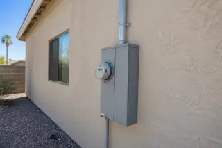 Screwdriver beside a masonry wall utility meter socket and overhead conduit in Phoenix, AZ.