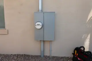 Utility meter socket and breaker enclosure on a stucco exterior wall in Phoenix, AZ.